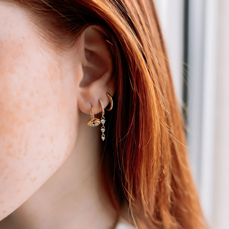Boucles d'oreilles GLOW THEORY Gold plaquées or portées en accumulation sur une oreille avec d'autres bijoux