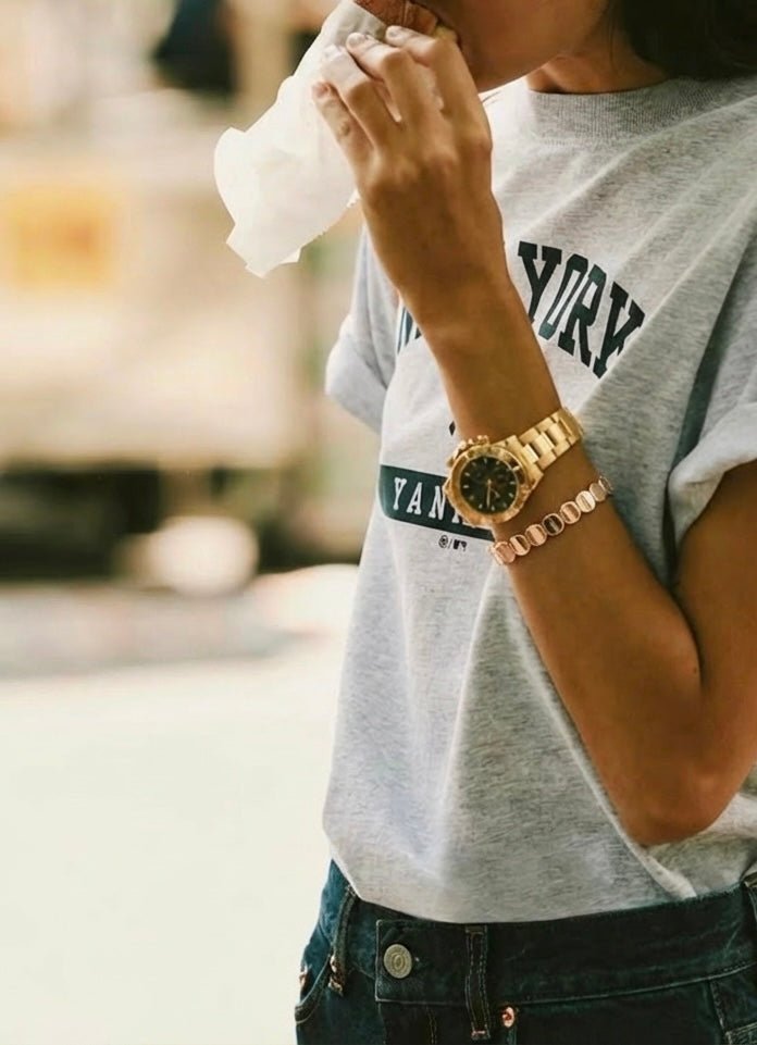 vue porté sur un poignet de femme qui mange un sandwich dans la rue