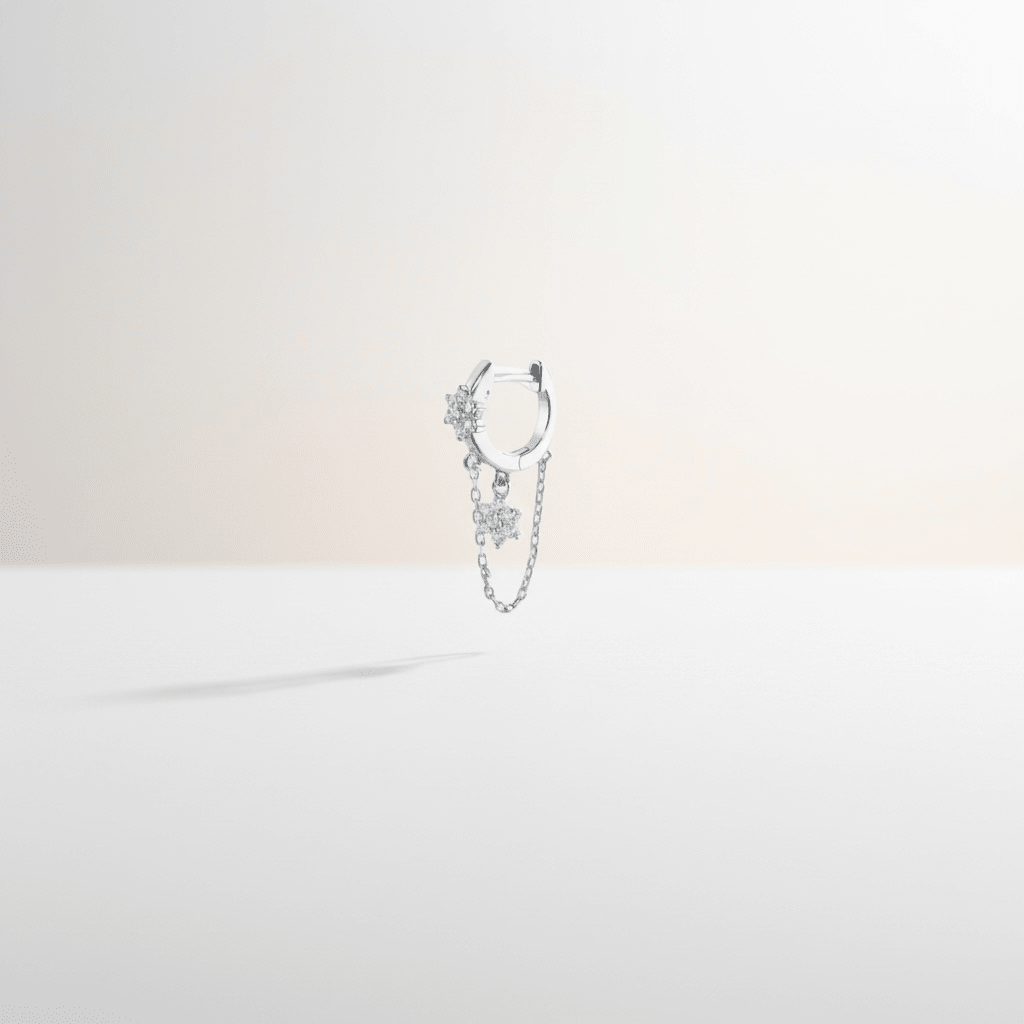 Mono boucle Iris Silver — fleur & étoile pavées zircons en argent 925 rhodié, chaînette fine. Hypoallergénique, résistante à l'eau. Éclat céleste délicat.