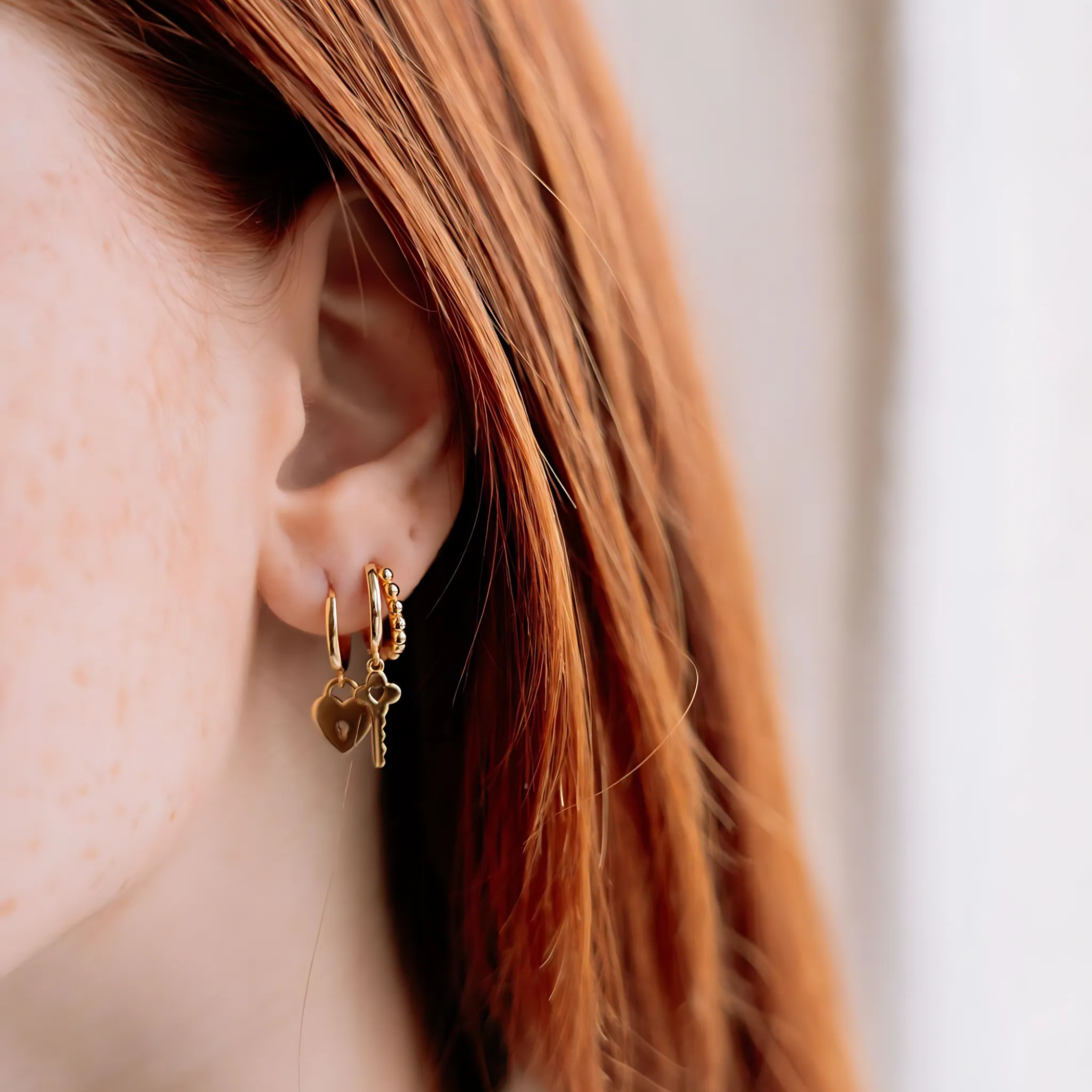 Boucles d'oreilles LOCK Gold plaquées or portées, créoles cœur-cadenas éclatantes et résistantes à l'eau. vue portée avec une boucle d'oreille Moxie et une boucle d'oreille Unlock en argent 925 plaqué or 18k 