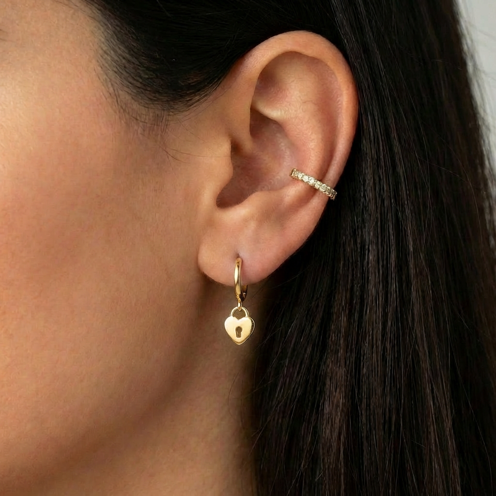 
Boucles Lock Gold — mini créoles charm cœur-cadenas en argent 925 plaqué or 18k. 8,5mm, hypoallergéniques, résistantes à l'eau. Vue portée par une femme brune