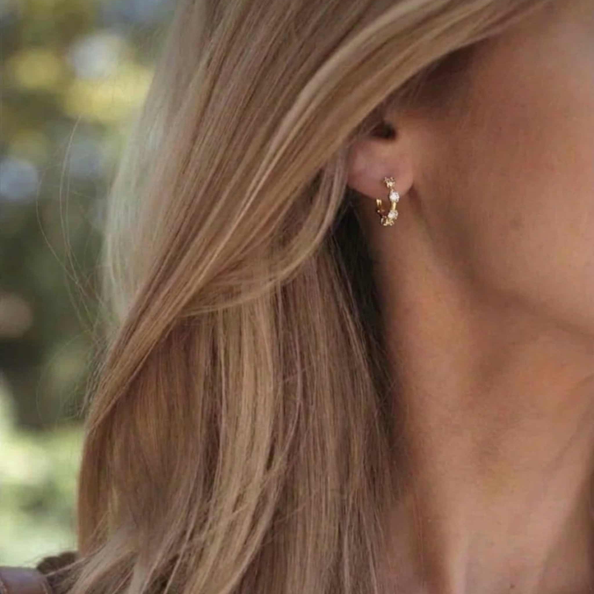 Mini créoles Lola en argent 925 plaqué or 18k & 5 zircones éclat diamant. Diamètre 9,6mm, hypoallergéniques, résistantes à l'eau. Discrètes et inoubliables. vue portée sur femme blonde 