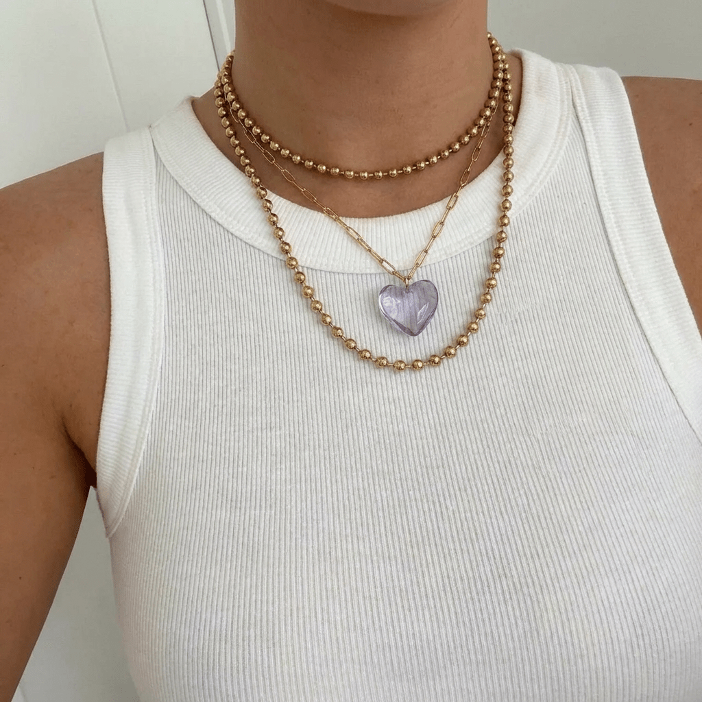 Collier Coco en acier inoxydable waterproof porté par une femme avec debardeur blanc et collier Cupidon parme